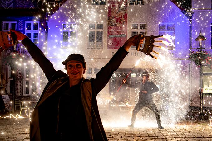 Schöne Frau mit Pyrotechnik im Hintergrund.